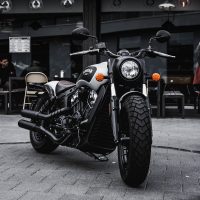 MOT checks black and gray cruiser motorcycle parked beside black concrete building