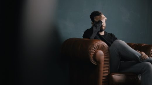 debt problem a man holds his head while sitting on a sofa