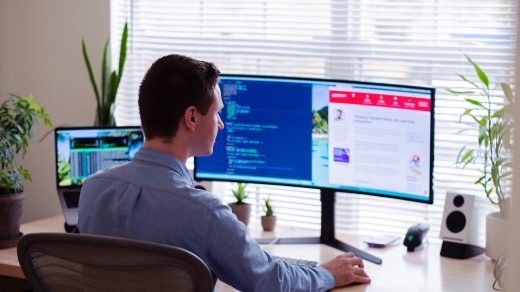 management software man in gray dress shirt sitting on chair in front of computer monitor