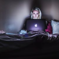 browser extensions Protect Your Privacy Online woman sitting on bed with MacBook on lap