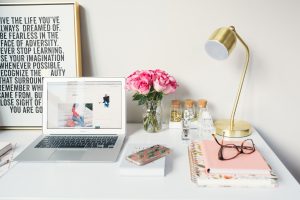 Small Business Blog MacBook Air beside gold-colored study lamp and spiral books