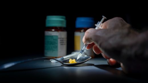addiction person using syringe on yellow stone on spoon