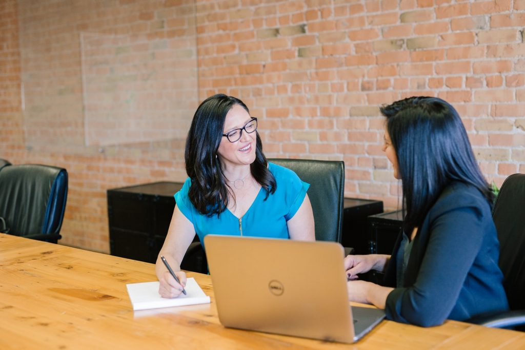 Leadership Coaching - woman in teal t-shirt sitting beside woman in suit jacket