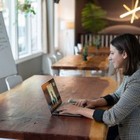 woman in gray and white striped long sleeve shirt using silver macbook