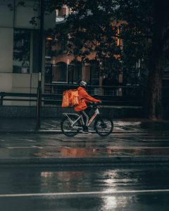 man in orange jacket riding bicycle on street during nighttime