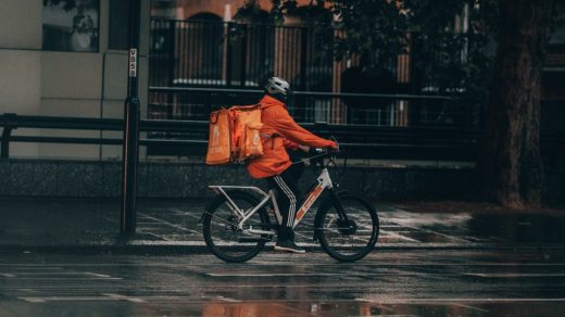 man in orange jacket riding bicycle on street during nighttime