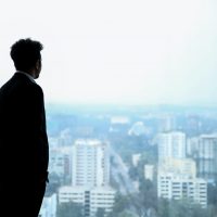 man in black suit standing on top of building looking at city buildings during daytime