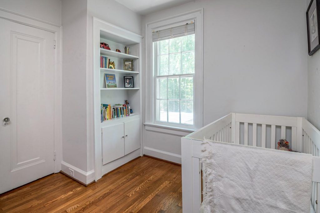 White wooden crib near a white wall in a nursery.