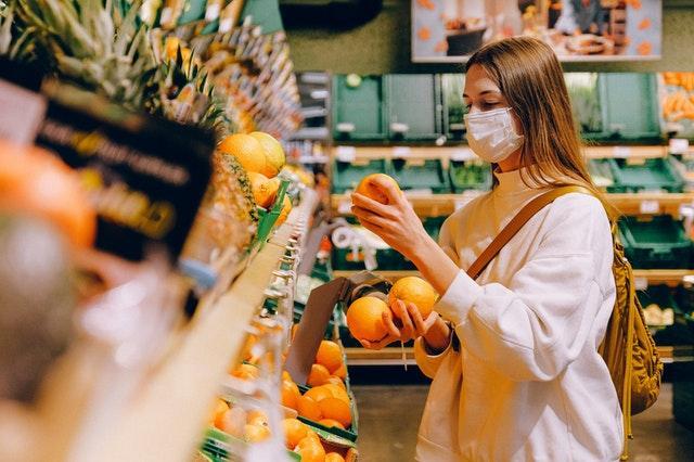 Girl picking out oranges in a grocery store. 
