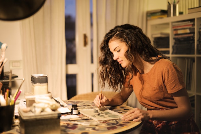 a woman painting at the living room table 