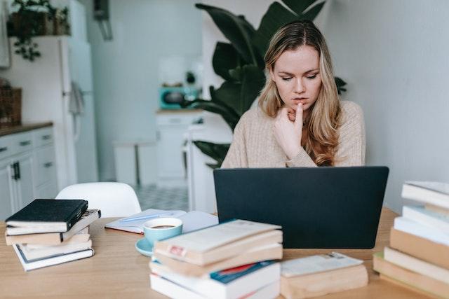 A woman doing research using books and a laptop.