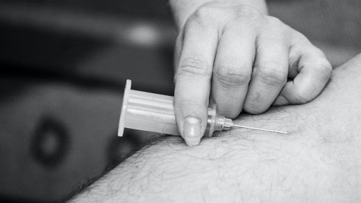 grayscale photo of person holding syringe