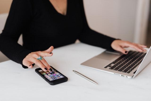 A woman in front of a laptop and a phone creating a plan for her entrepreneurship journey on overcoming rejection.