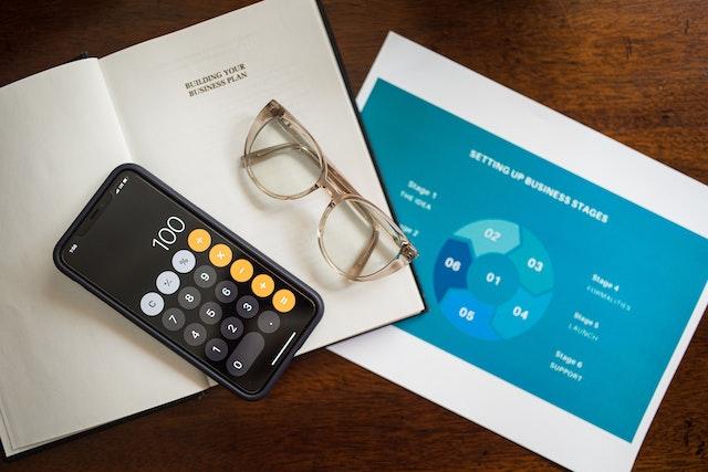 A book on building a business plan, a diagram of the business stages, and a phone calculator.