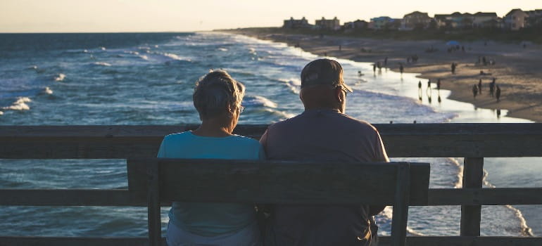 Retirement Relocation: Finding Your Ideal Retirement Destination 1 A retired couple sitting on a bench looking at the coastline