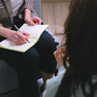 Crop counselor writing in diary while talking to patient