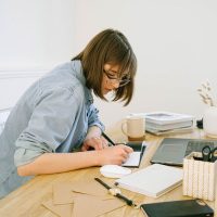 Woman sitting at a desk with a laptop and a notebook