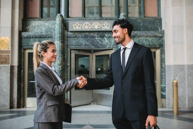 Business partners shake hands in front of a building