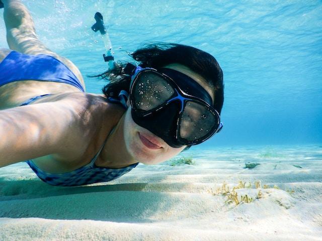 Woman in a blue swimsuit with goggles underwater