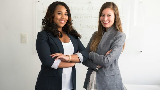 two women in suits standing beside wall