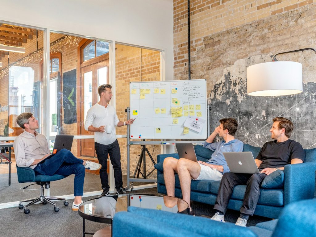 Recognizing Employee Needs For a Better Business Performance 1 three men sitting while using laptops and watching man beside whiteboard