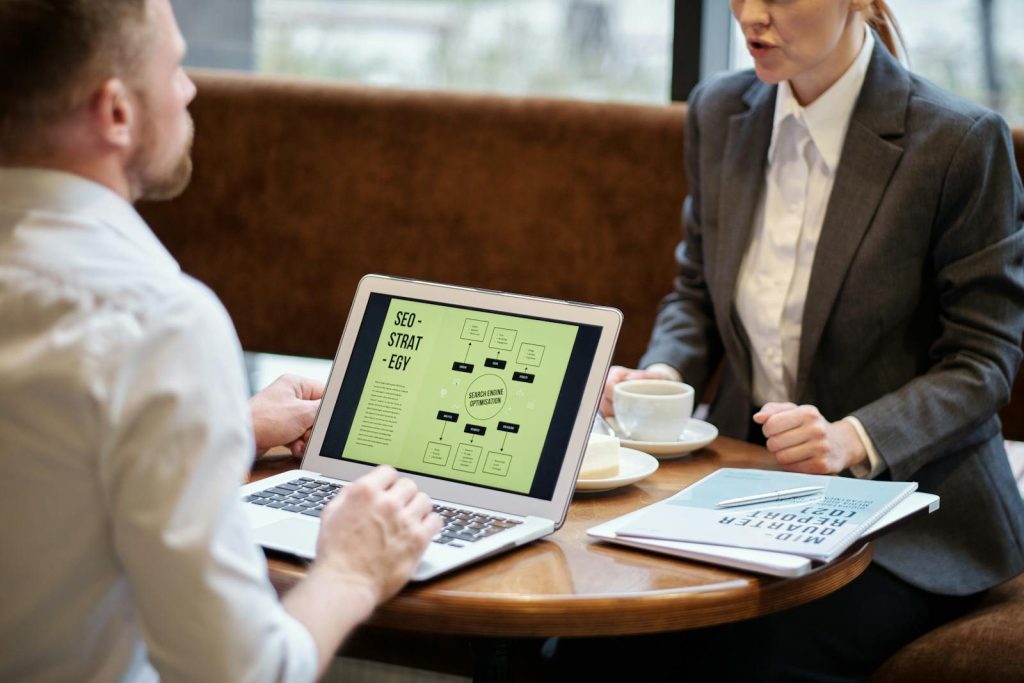 Smart Technical SEO Fixes That Help Search Engines Trust Your Site 1 A man and woman engaged in a business meeting discussing SEO strategy in a cozy cafe setting.